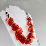 Necklace with orange beads on a white stand against a gray background